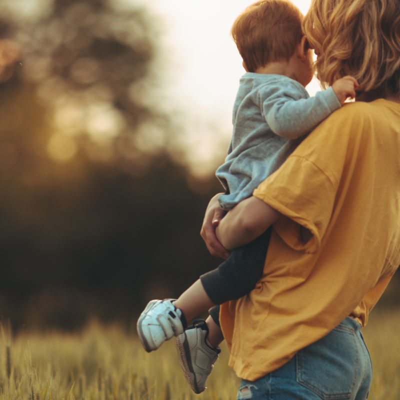 mom holding baby boy in field little blessings